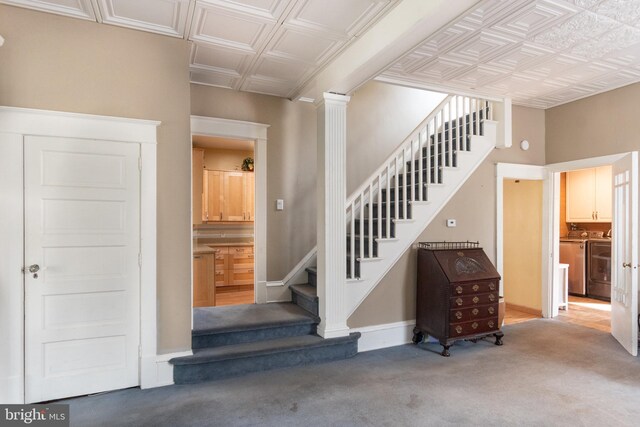 stairs with carpet, washer and clothes dryer, and decorative columns