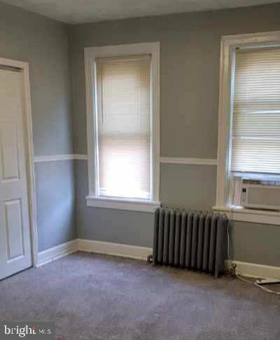 empty room with carpet, radiator, and cooling unit