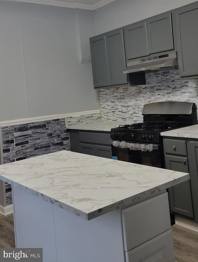 kitchen with backsplash, gray cabinets, crown molding, wood-type flooring, and black gas stove