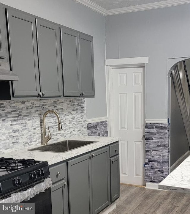 kitchen featuring gray cabinets, light hardwood / wood-style flooring, black gas range oven, and sink