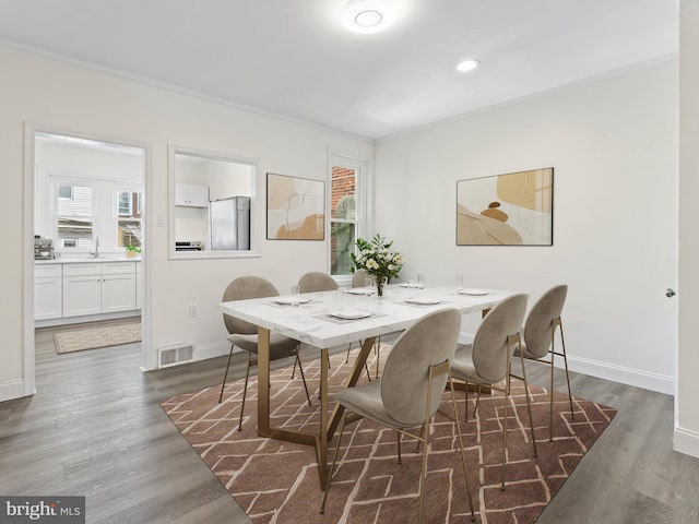 dining room featuring sink, dark wood-type flooring, and ornamental molding