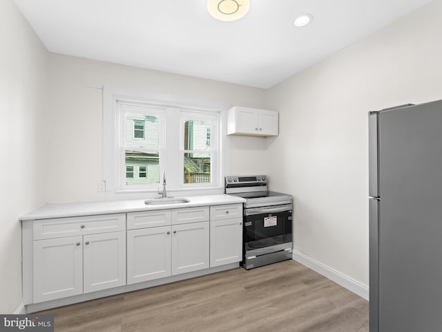 kitchen with sink, light hardwood / wood-style flooring, white cabinets, and appliances with stainless steel finishes