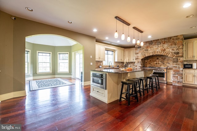 kitchen featuring dark wood-type flooring, a breakfast bar area, and dark stone counters