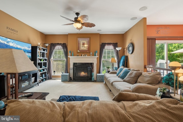 living room with ceiling fan, light carpet, and a fireplace