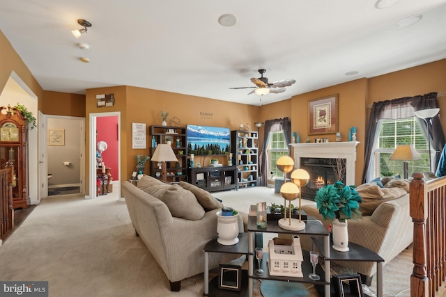 carpeted living room with ceiling fan and a fireplace