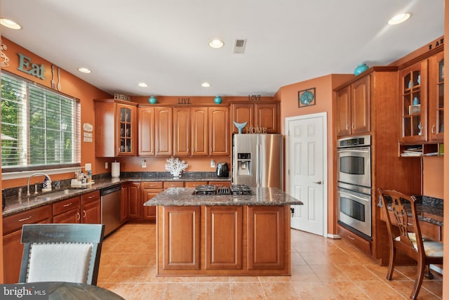 kitchen featuring appliances with stainless steel finishes, dark stone countertops, sink, and a kitchen island