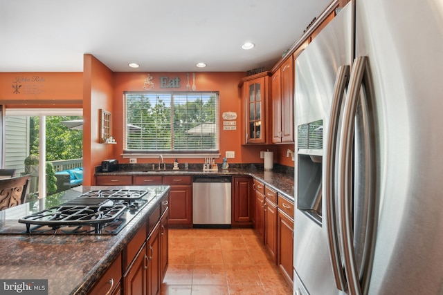 kitchen with appliances with stainless steel finishes, dark stone counters, and light tile patterned flooring