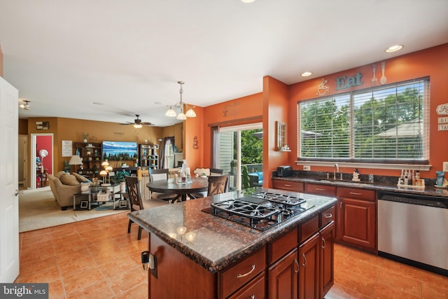 kitchen featuring stainless steel appliances, decorative light fixtures, a center island, light tile patterned flooring, and ceiling fan with notable chandelier