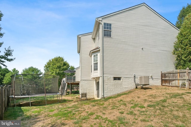 view of home's exterior with central AC, a lawn, and a trampoline