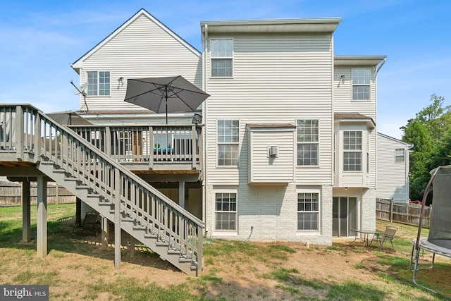 back of property featuring a wooden deck and a trampoline