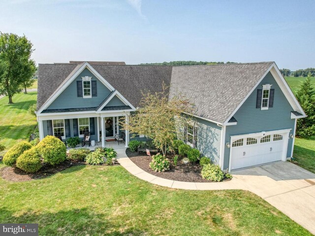 view of front of home featuring a front yard, a garage, and covered porch