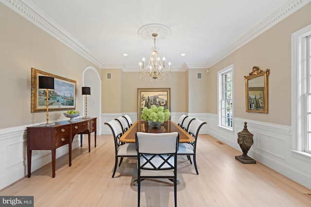 dining area featuring visible vents, ornamental molding, wainscoting, light wood finished floors, and an inviting chandelier