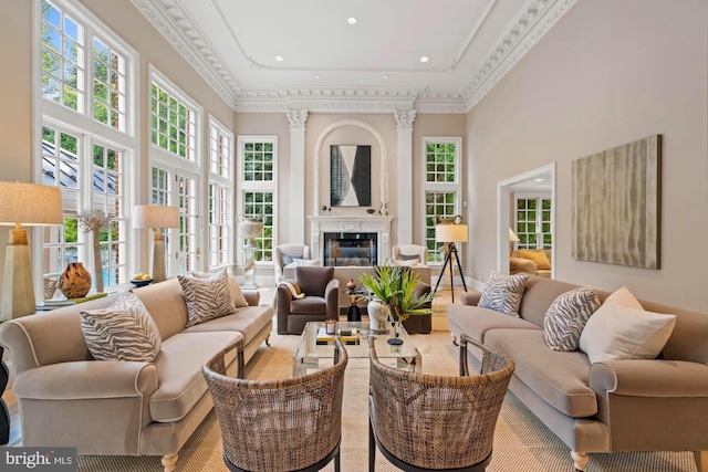 living area featuring a high ceiling, ornamental molding, and a high end fireplace