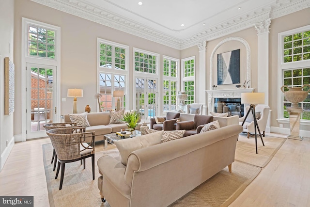 living area with light wood-type flooring, a towering ceiling, and crown molding