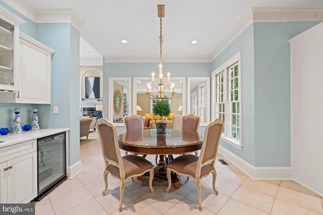 dining area with light tile patterned floors, beverage cooler, ornamental molding, and a chandelier