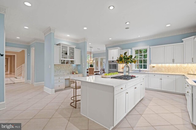 kitchen featuring a kitchen bar, a kitchen island, decorative backsplash, and white cabinetry