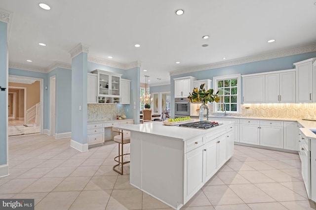 kitchen with appliances with stainless steel finishes, light countertops, a kitchen island, and light tile patterned floors