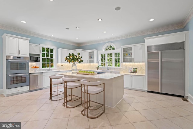 kitchen featuring stainless steel appliances, a breakfast bar, white cabinets, and light tile patterned floors