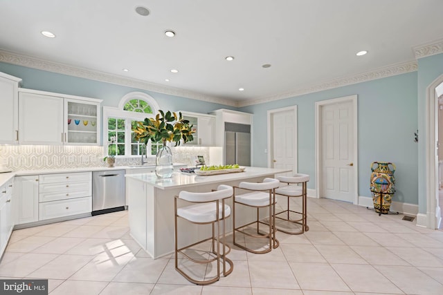 kitchen with light tile patterned flooring, stainless steel appliances, a kitchen island, light countertops, and tasteful backsplash