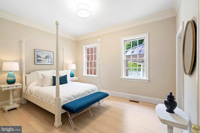 bedroom with visible vents, crown molding, light wood-style flooring, and baseboards