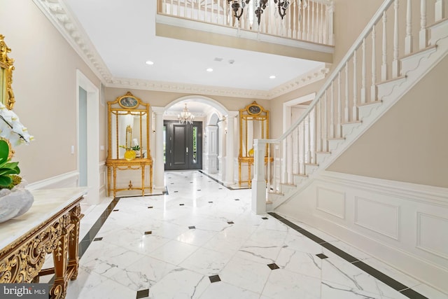 entryway featuring arched walkways, ornamental molding, stairway, and a decorative wall