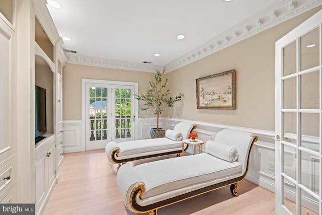 living area with a wainscoted wall, french doors, light wood finished floors, and crown molding