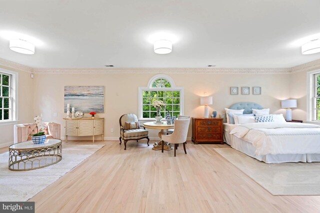 bedroom with crown molding, light hardwood / wood-style flooring, and multiple windows