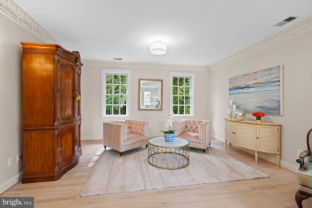 living area featuring light wood-style floors, visible vents, and crown molding