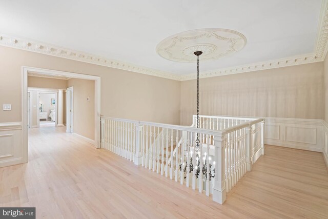 corridor with a notable chandelier, light hardwood / wood-style floors, and crown molding