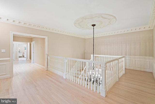 corridor with a wainscoted wall, a decorative wall, and wood finished floors