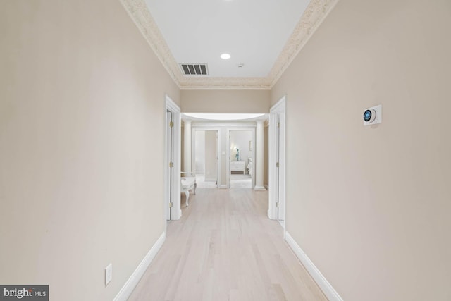 hall with baseboards, visible vents, light wood-style flooring, and ornamental molding