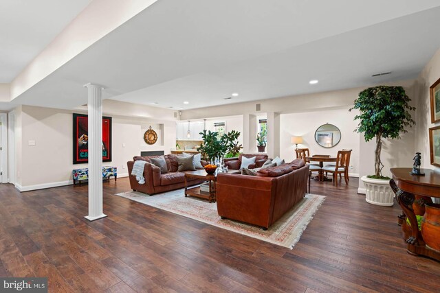 living room featuring dark wood-type flooring and decorative columns