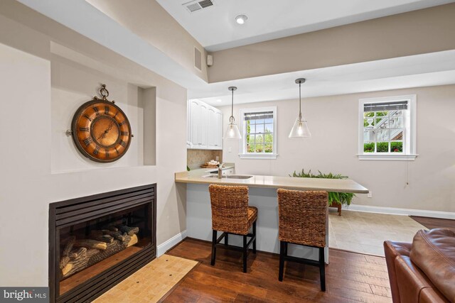 interior space with backsplash, dark hardwood / wood-style flooring, sink, kitchen peninsula, and a breakfast bar