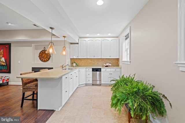 kitchen featuring a breakfast bar, decorative backsplash, white cabinets, a sink, and a peninsula