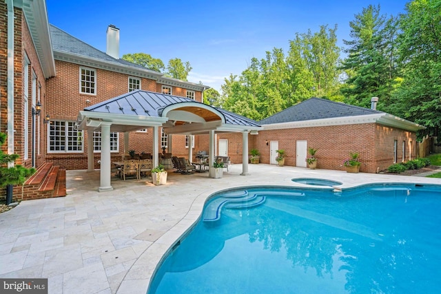 pool featuring a patio area, outdoor dining area, and an in ground hot tub