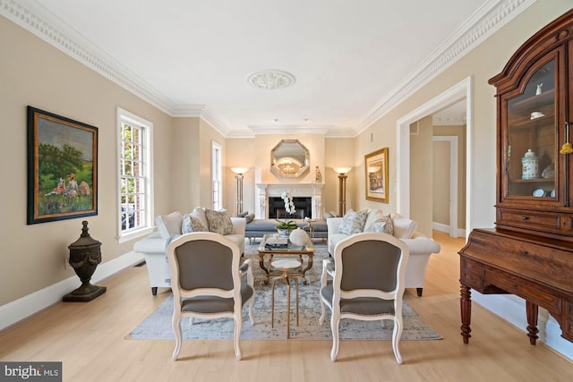 living room with baseboards, ornamental molding, a fireplace, and light wood-style floors