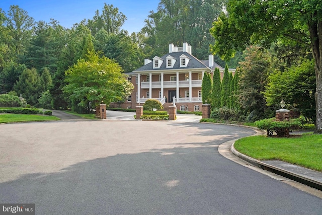 greek revival inspired property with aphalt driveway and a porch