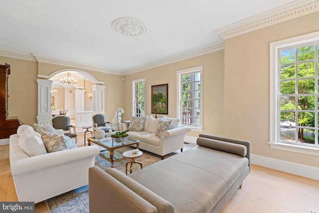 living area with decorative columns, crown molding, baseboards, and a wealth of natural light