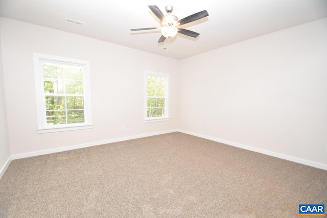 empty room featuring plenty of natural light, carpet flooring, and ceiling fan