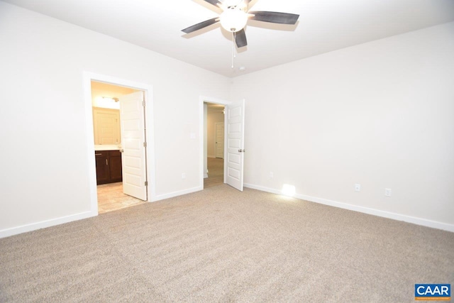 unfurnished bedroom featuring ceiling fan, light colored carpet, and ensuite bath