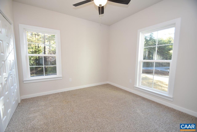 empty room with carpet flooring, a wealth of natural light, and ceiling fan