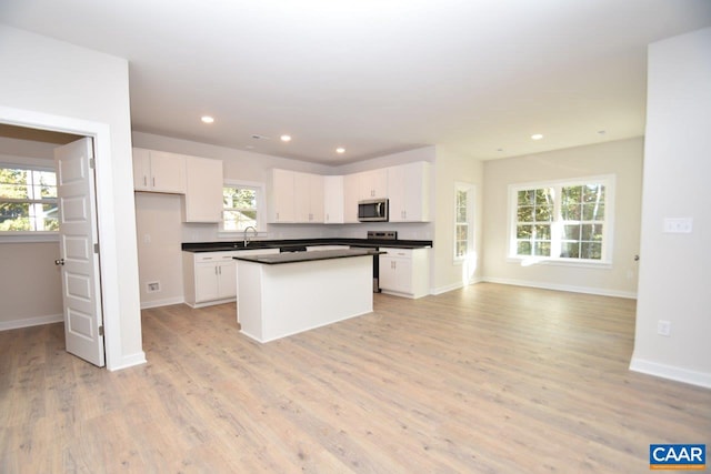 kitchen featuring white cabinetry, a center island, sink, and light hardwood / wood-style flooring