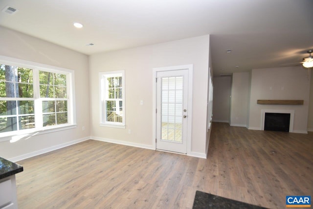 unfurnished living room featuring ceiling fan, plenty of natural light, and wood-type flooring