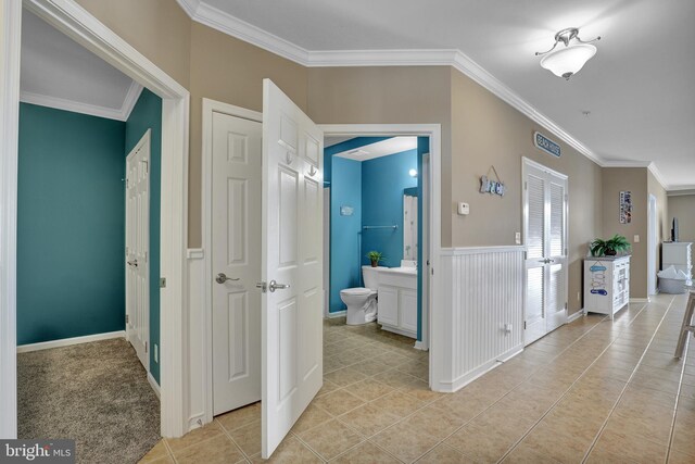 bathroom featuring toilet, tile patterned floors, crown molding, vanity, and a tile shower