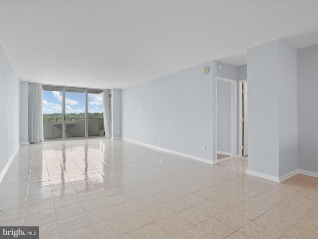 unfurnished room featuring floor to ceiling windows, baseboards, and light tile patterned floors