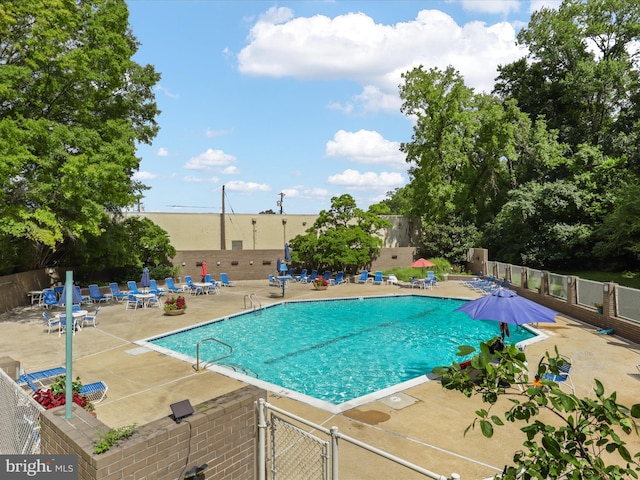 community pool with a patio area and fence