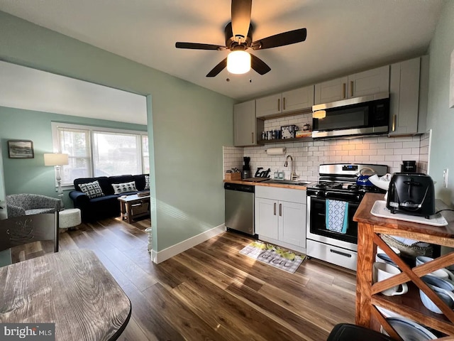 kitchen featuring appliances with stainless steel finishes, dark hardwood / wood-style floors, tasteful backsplash, gray cabinetry, and ceiling fan