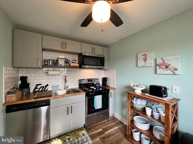 kitchen with stainless steel appliances, tasteful backsplash, sink, ceiling fan, and dark wood-type flooring