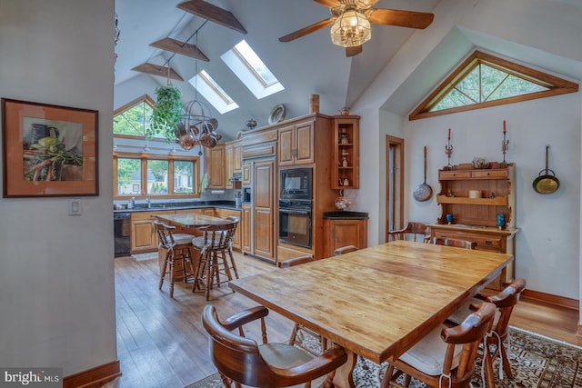 dining room featuring a skylight, ceiling fan, plenty of natural light, and light hardwood / wood-style floors