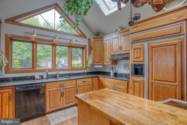 kitchen with sink, dishwasher, wooden counters, paneled built in fridge, and vaulted ceiling with skylight